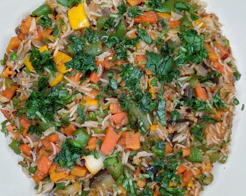 Plate of vegetable fried rice topped with fresh cilantro