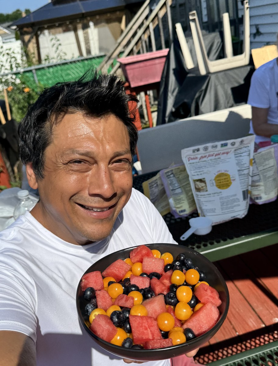 Jose holding a large plate of fresh fruit and vegetables outdoors